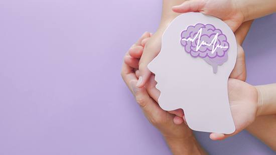 Understanding lucid episodes in dementia Hands hold a paper cutout of the profile of a human head with a brain; isolated on a purple background.