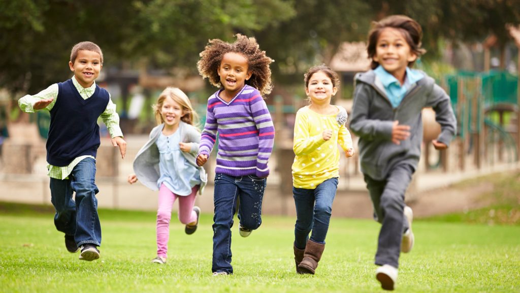a group of happy children running and smiling near a playground