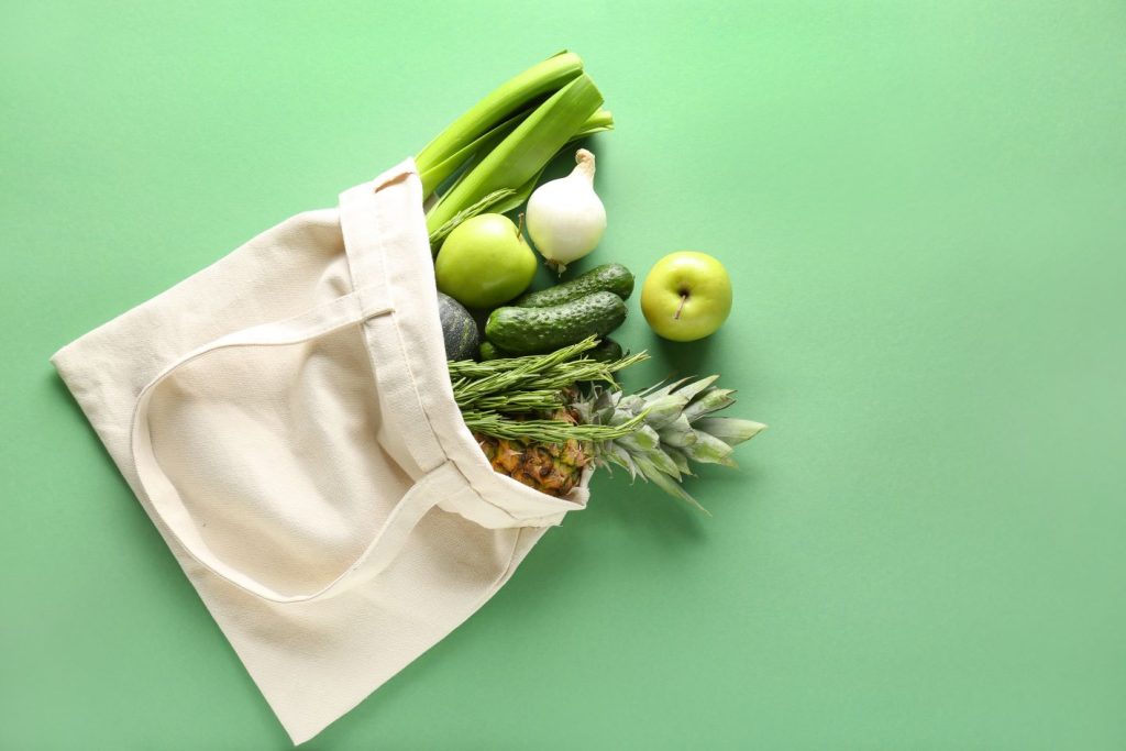 Fresh green vegetables in a beige canvass bag